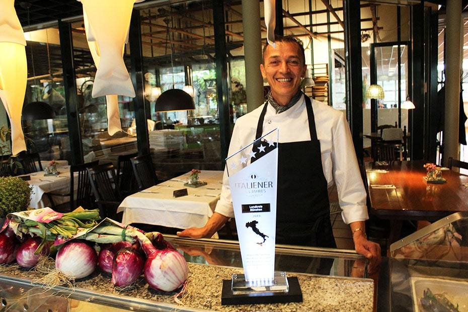 Der Küchenchef mit der Trophäe vor der Vitrine