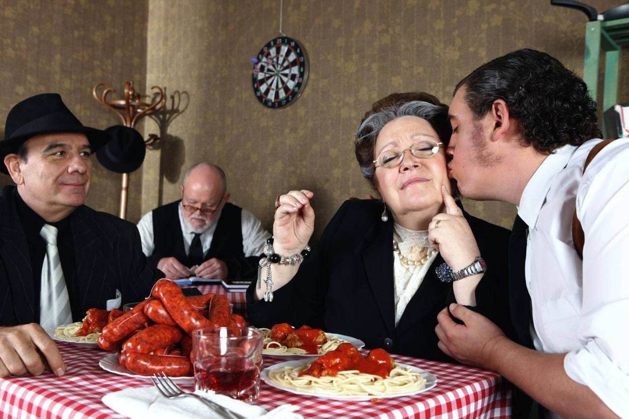 Die Nonna bekommt am gedeckten Tisch einen Kuss, davor Hummer und Spaghetti