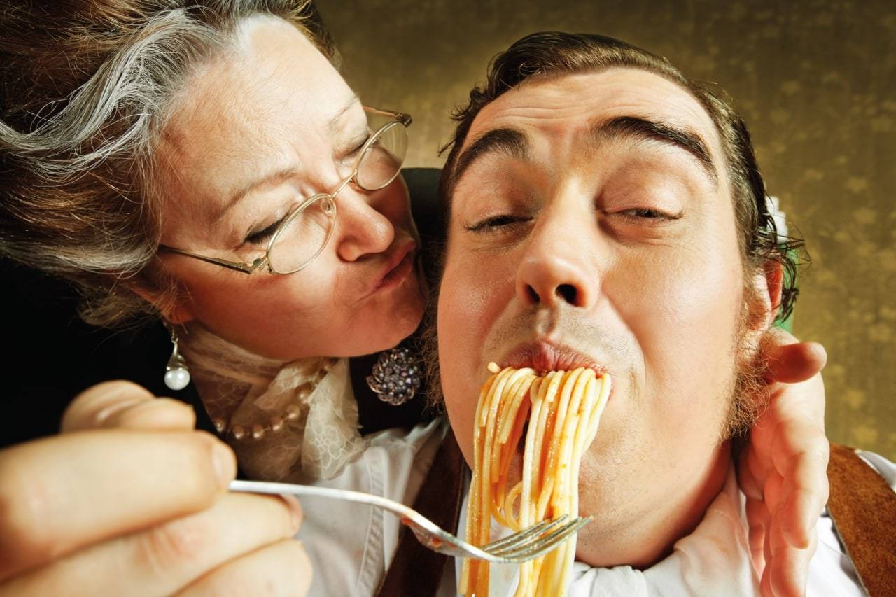 Nonna küsst ihren Sohn, der genüsslich Spaghetti isst