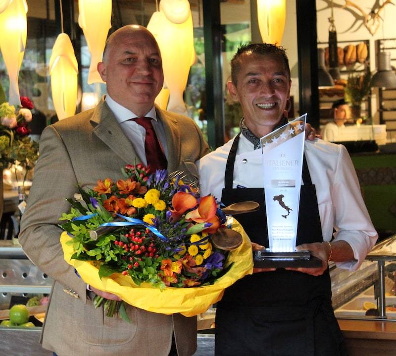 Klaus Holzapfel und Küchenchef mit Trophäe und Blumen